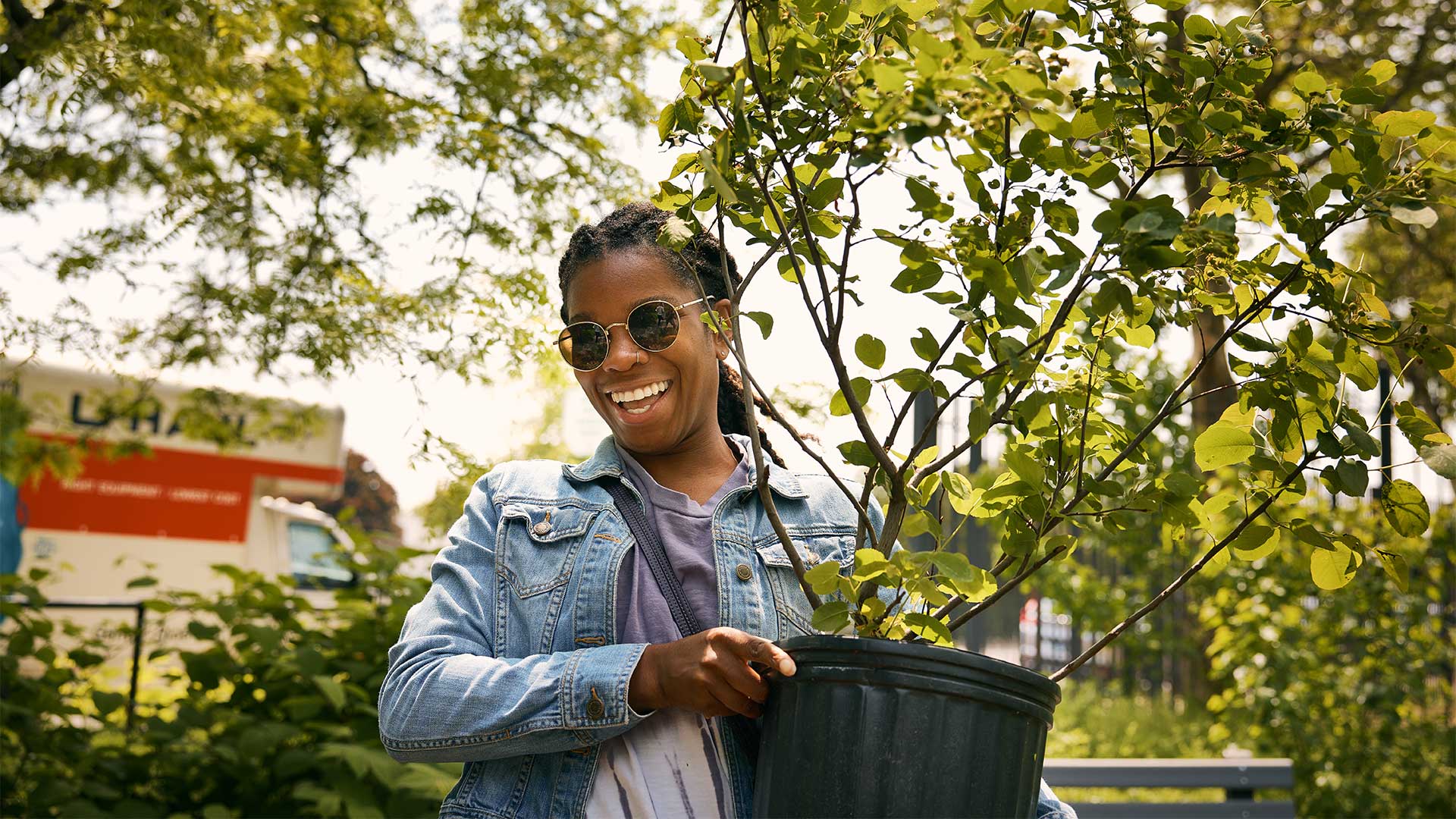 woman holding a potted tree at a tree distribution