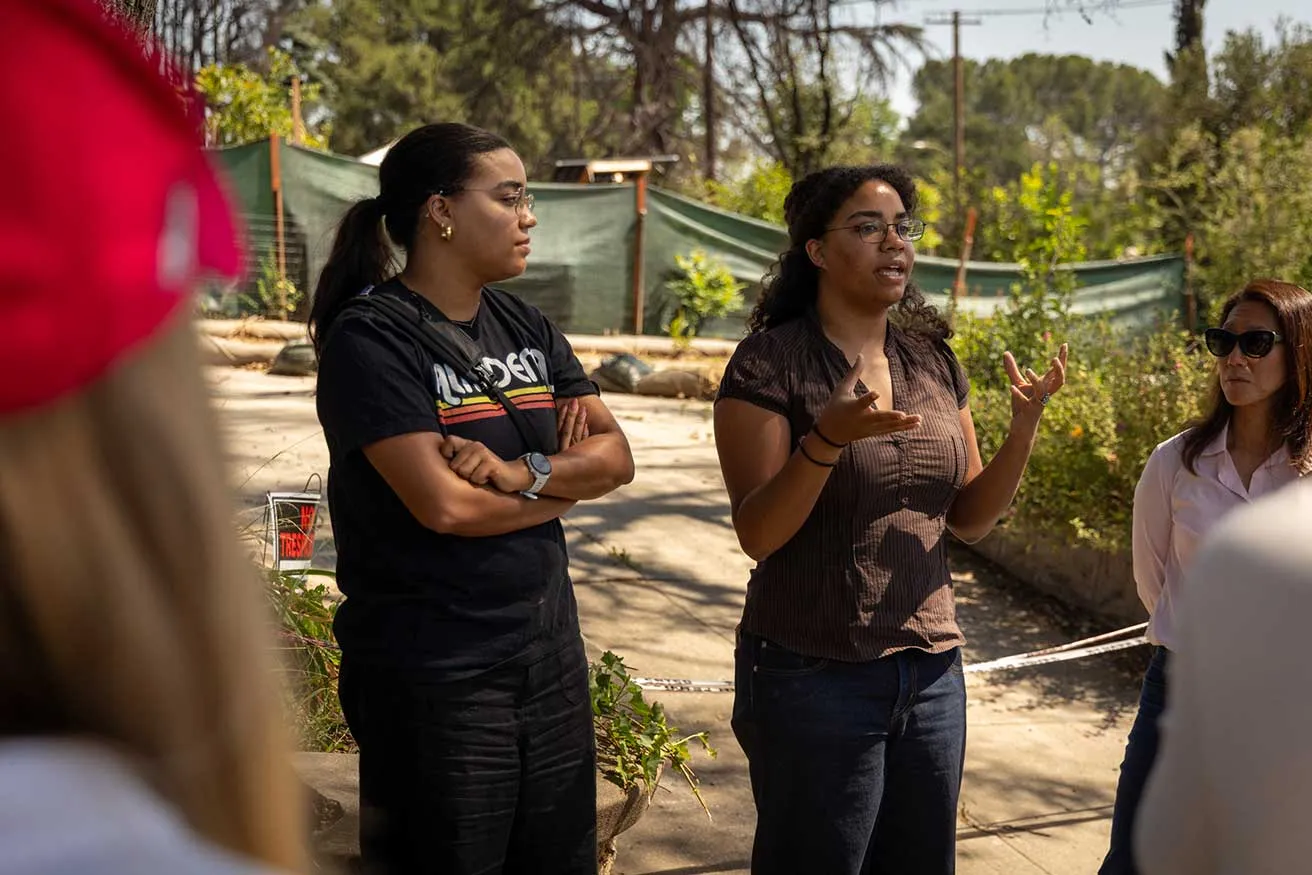 Three women engaged in conversation while standing together in a casual setting.