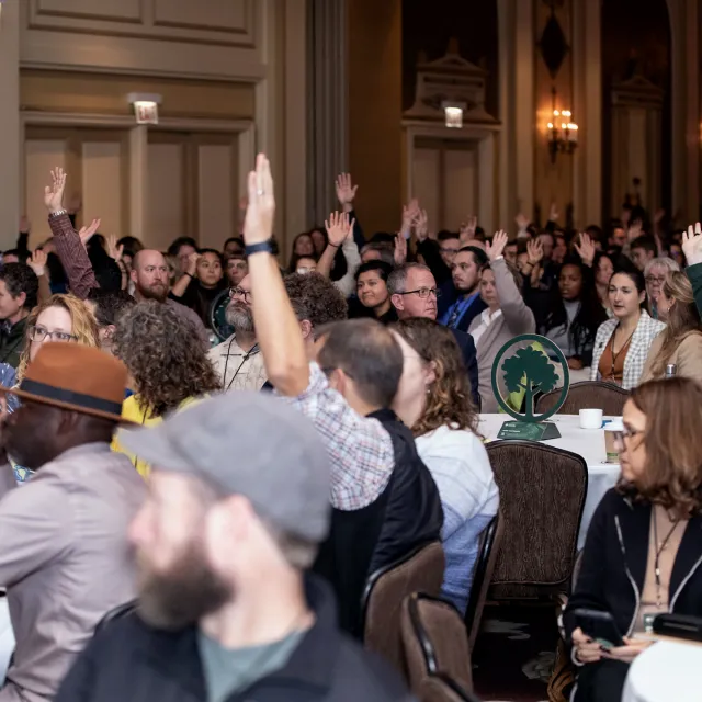 People raising their hands at a conference session