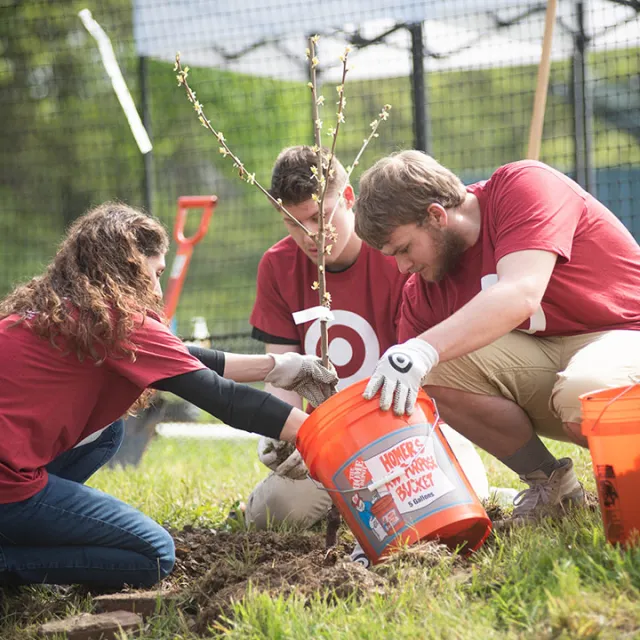 A group of people planting a tree in red shirts
