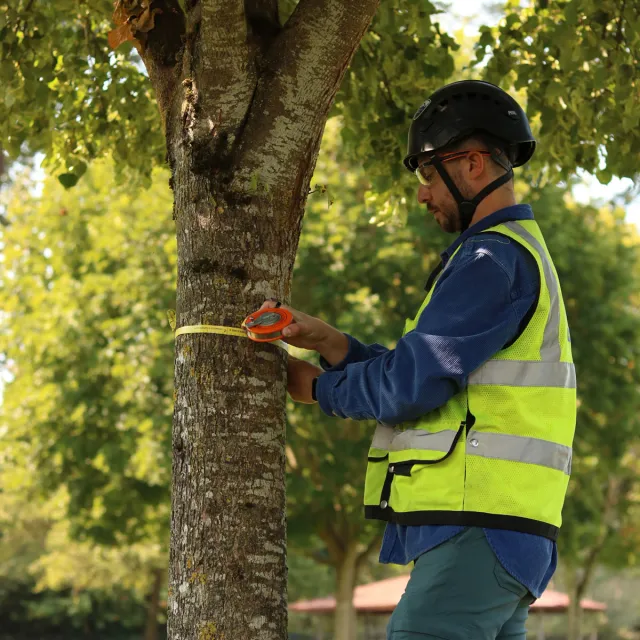A man wearing a bright yellow safety vest stands outdoors, emphasizing visibility and safety in his environment.