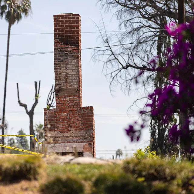A brick chimney surrounded by yellow caution tape, indicating a potential hazard or area under maintenance.