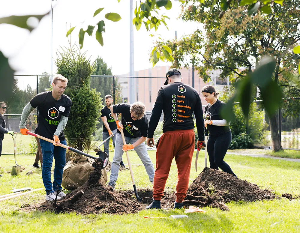 A diverse group of people collaborating to cultivate a garden, planting trees together.
