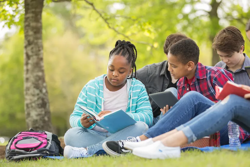 group of middle school students sitting under a tree and talking