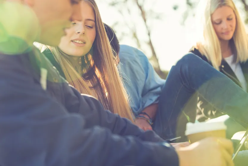 high school students studying outside under shade trees