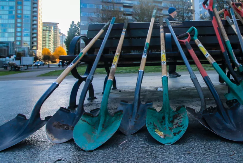 stack of shovels with city skyline in the background